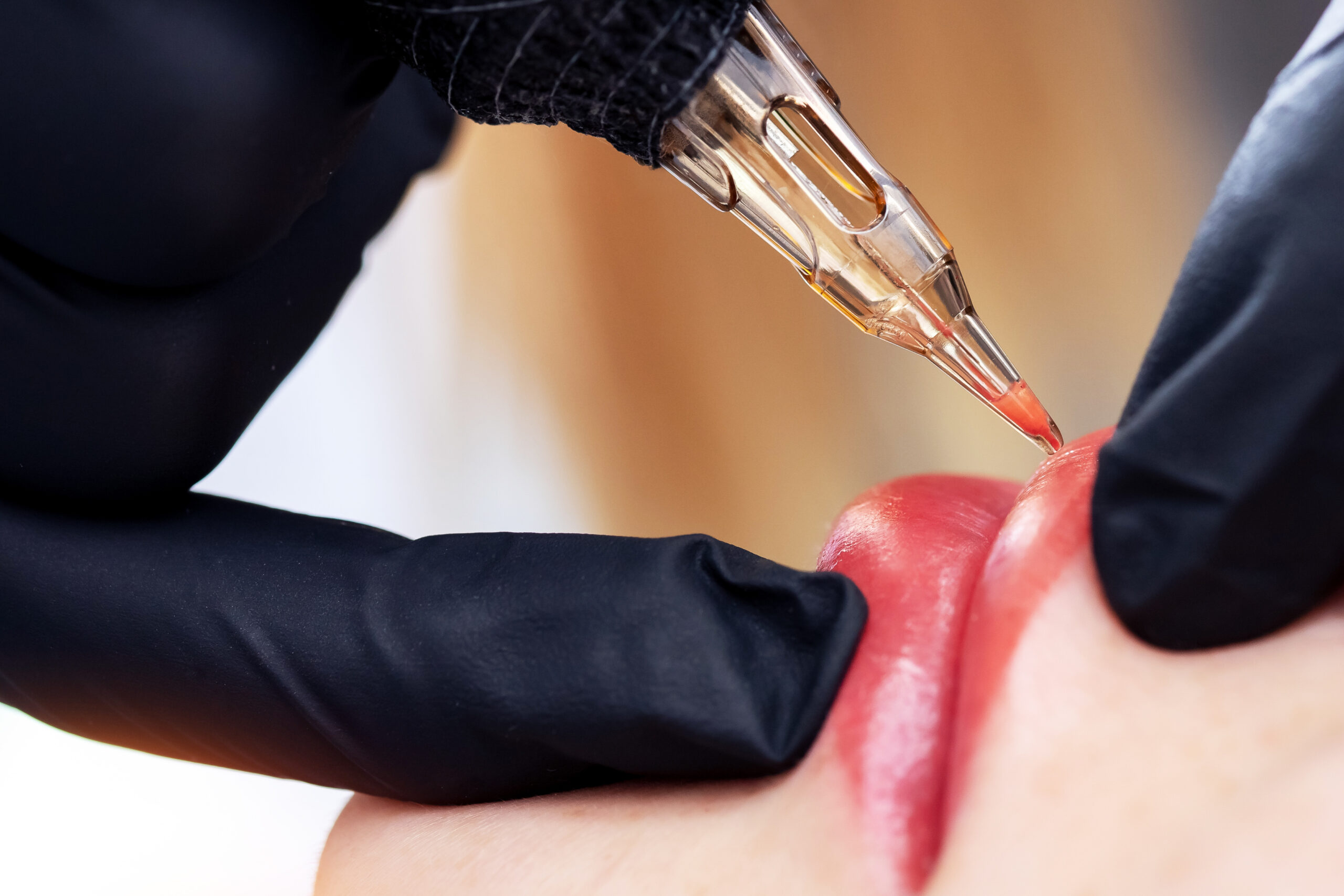 Healing Skin Medical Aesthetics - Applying red pigment with tattoo machine on woman lips, permanent makeup in beauty salon.