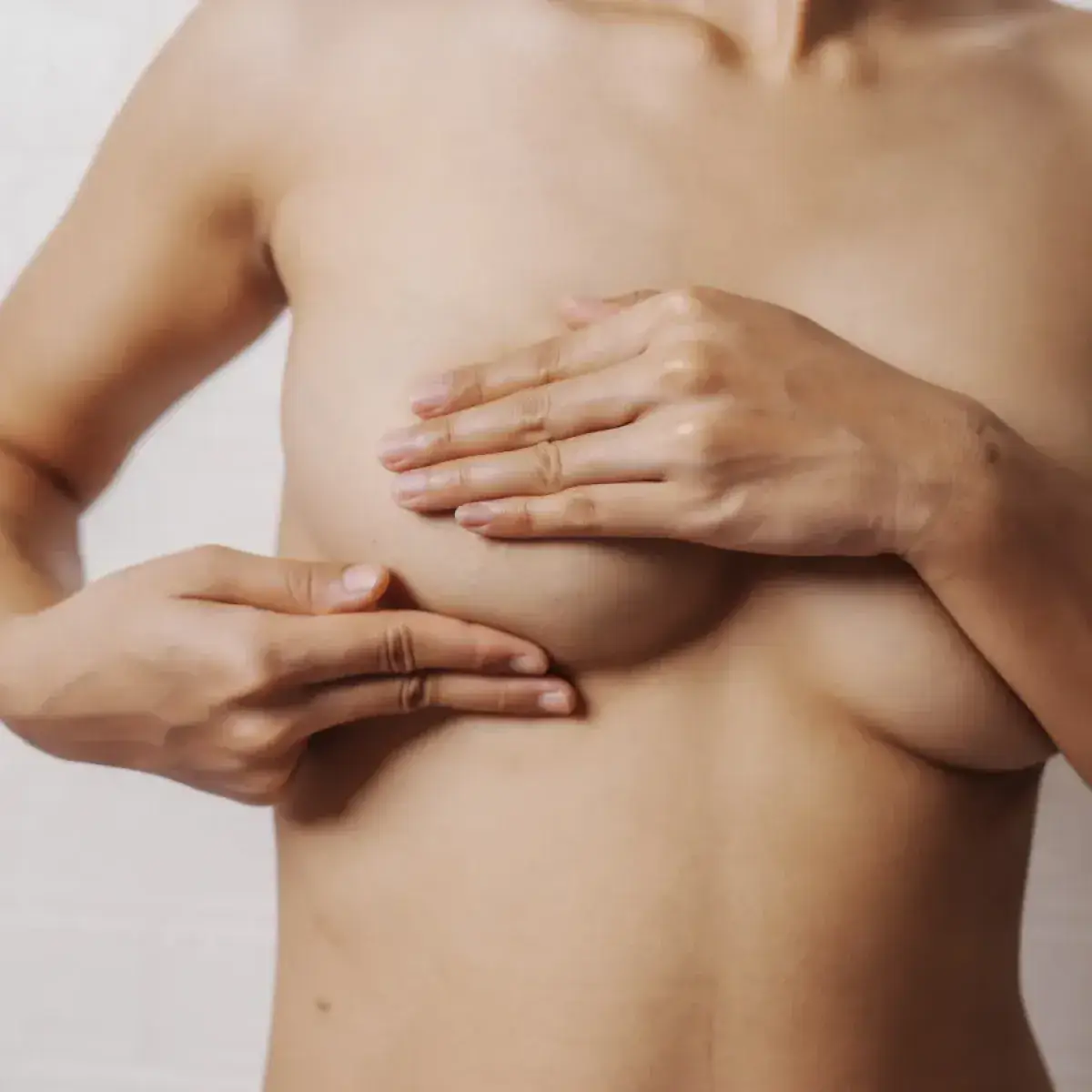 Close-up of a woman covering her chest before receiving a 3D areola tattoo for areola restoration.